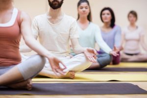 Group of people sitting in lotus position in the fitness studio